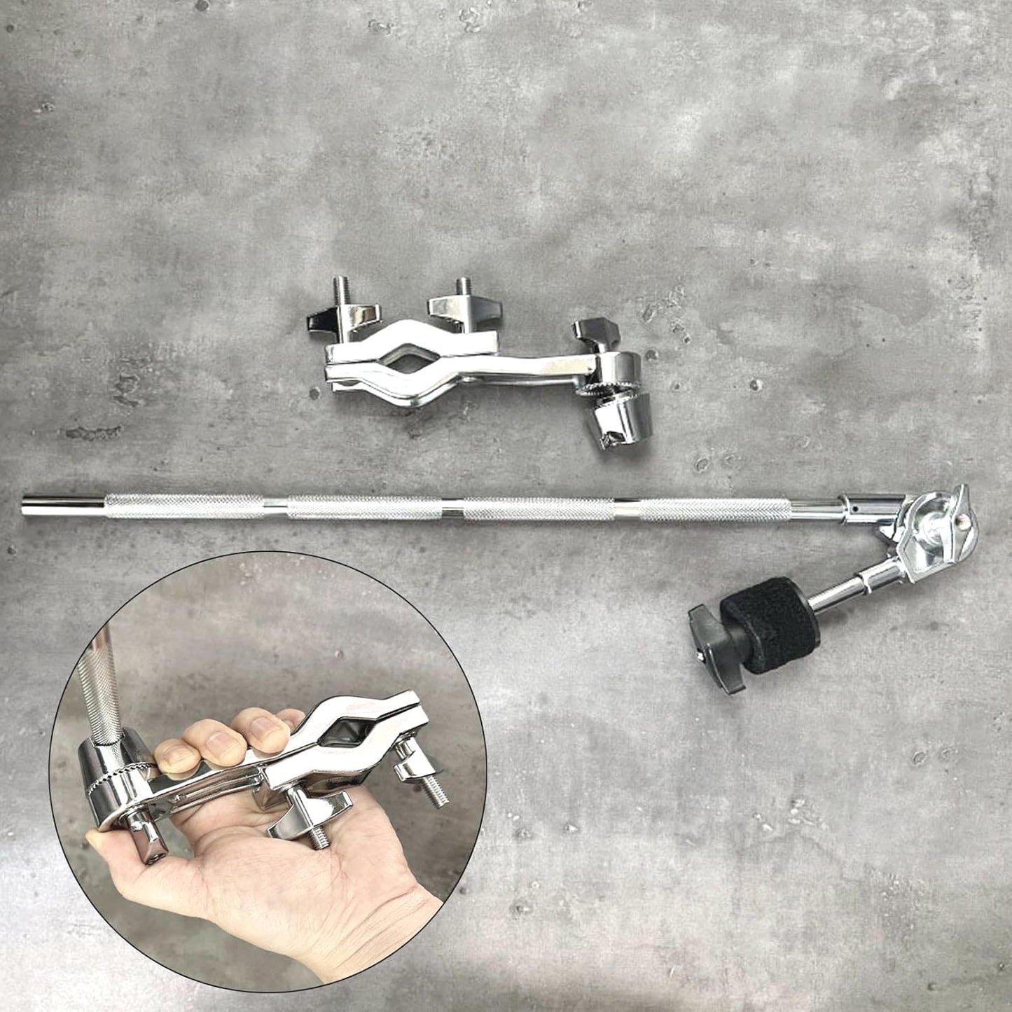 Chrome metal clamps and bar on a gray concrete background with close-up of hand holding clamp.