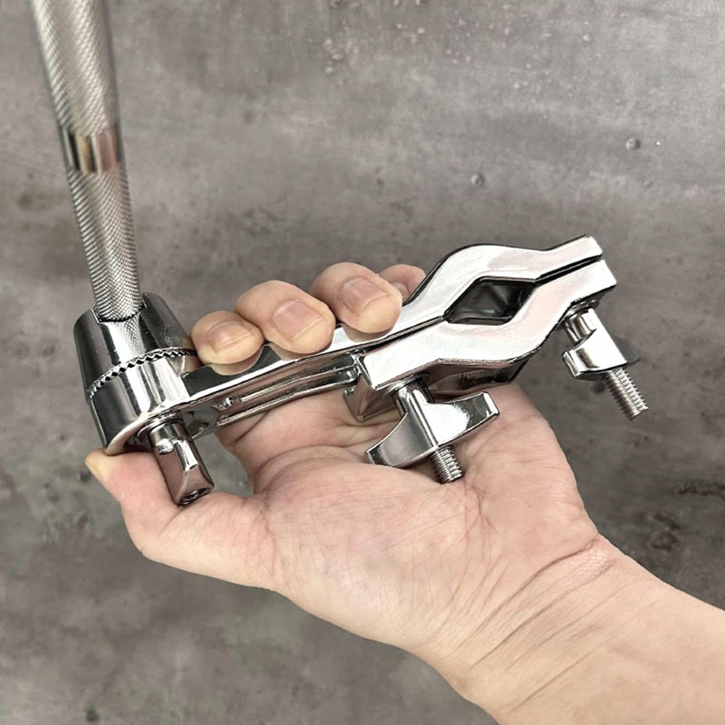Hand holding a metallic clamp against a gray background