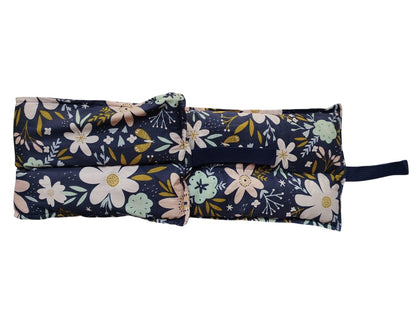 Floral-patterned fabric roll-up with a strap on a white background