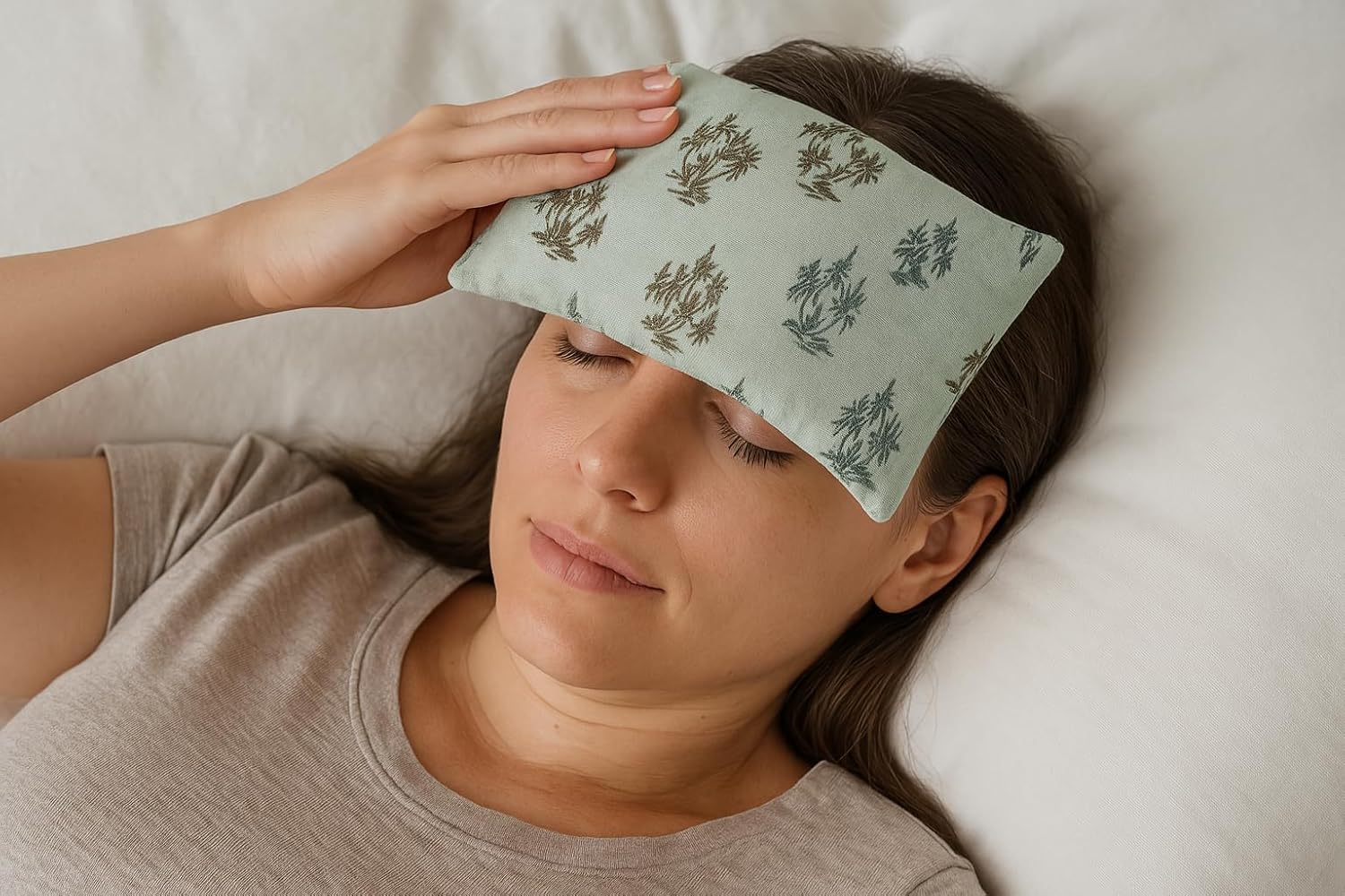 Woman wearing a light green eye mask with floral patterns on a white pillow.