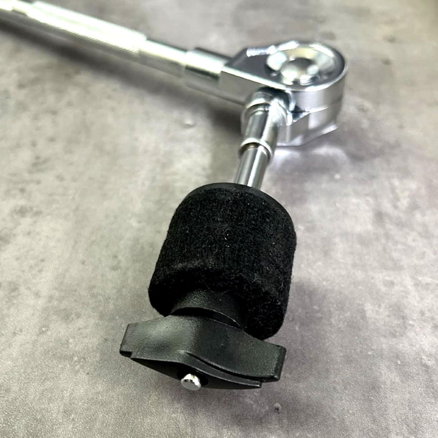 Close-up of a metal tool with a black foam pad on a gray surface